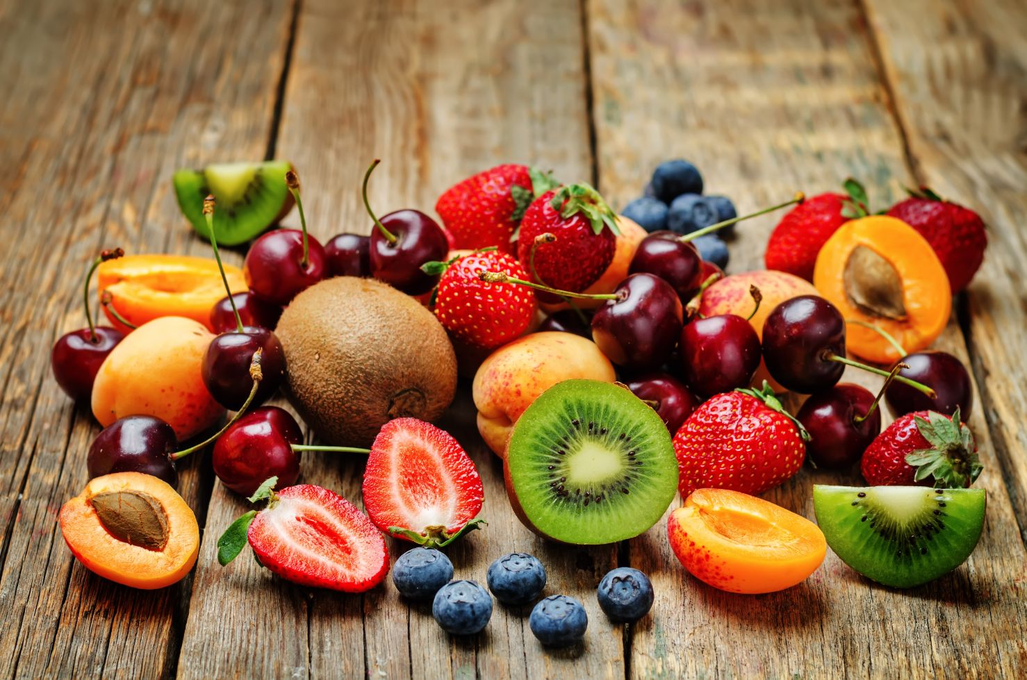 Collection of fruits and berries on wood table.
