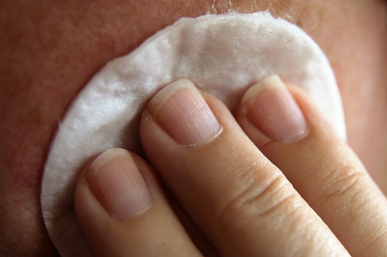 Woman blotting her skin with makeup remover cotton.